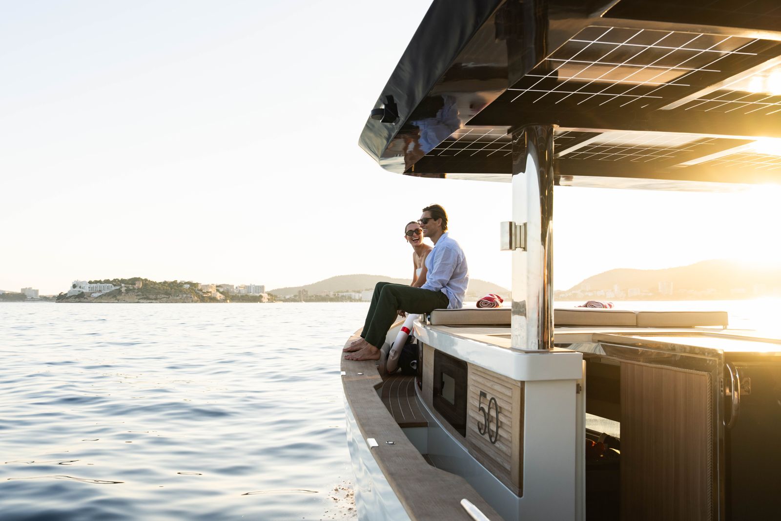 Guests on the stern of the SAMAR 50 at sunset, with the 50 emblem