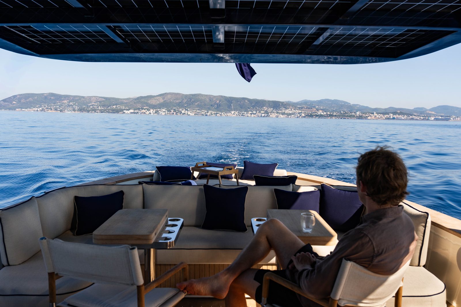 A guest in the aft lounge under the solar roof, looking out to the coast